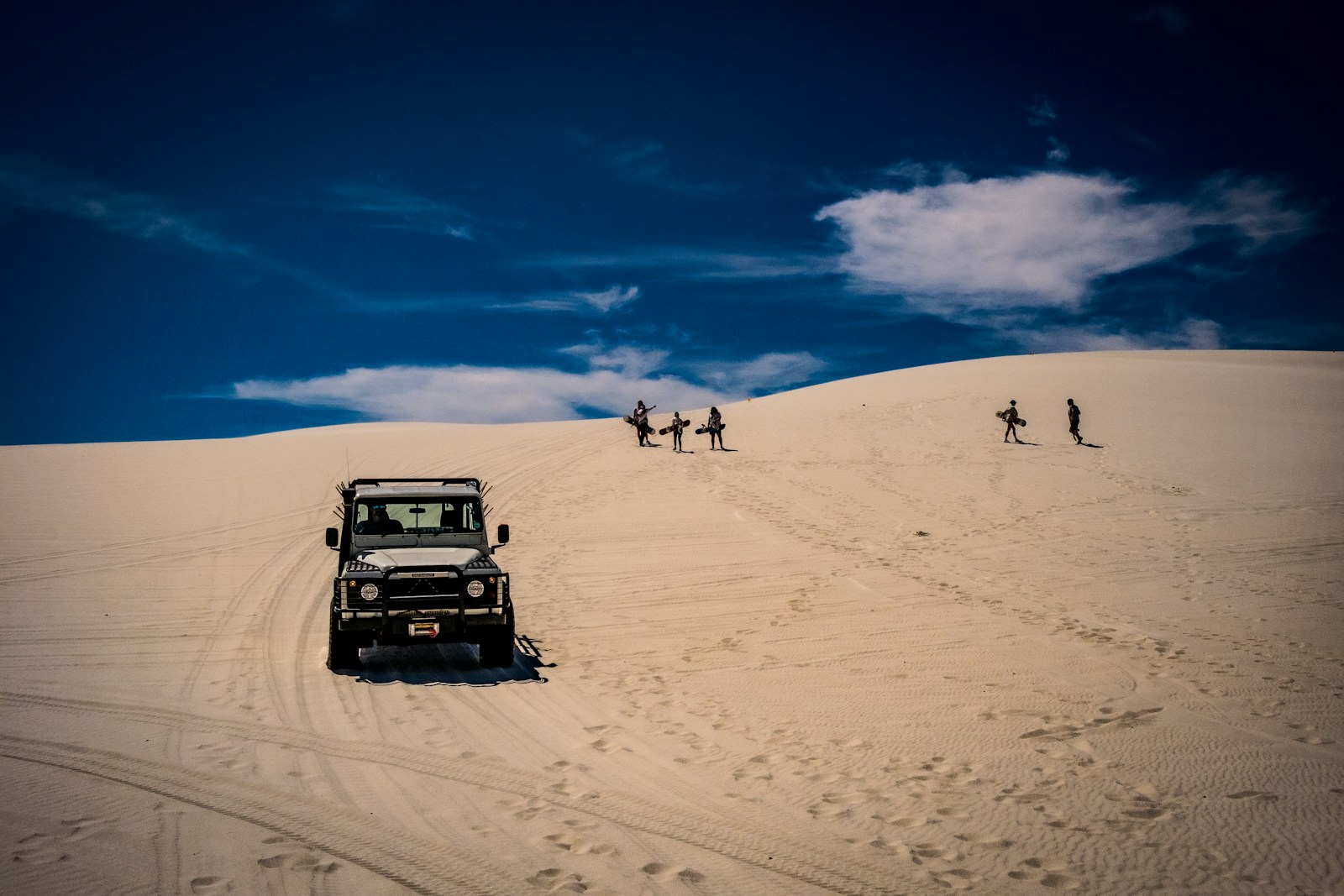 a jeep driving down a sandy hill in the desert